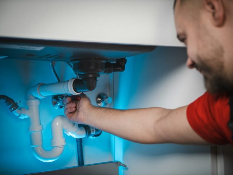 Plumber repairing pipes under a sink for a local home service business