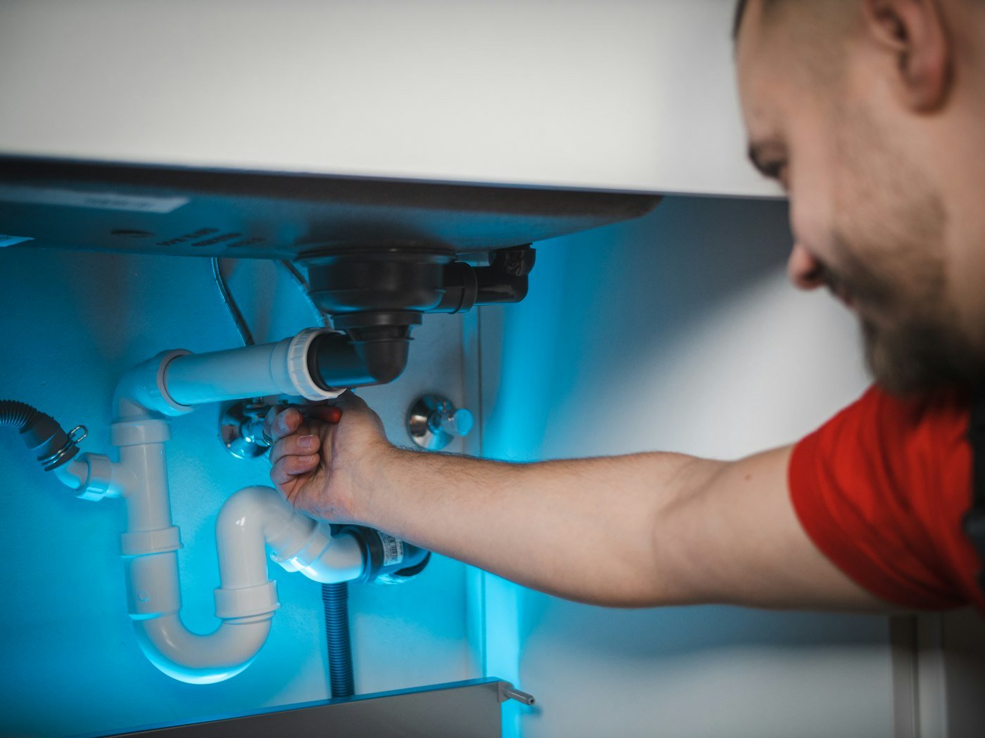 Plumber repairing pipes under a sink for a local home service business